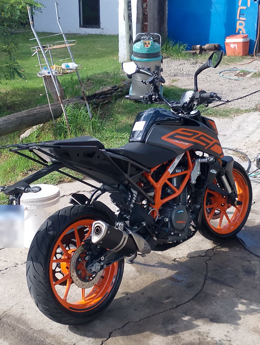 Una moto KTM naranja y negra en el patio, con la aspiradora atrás