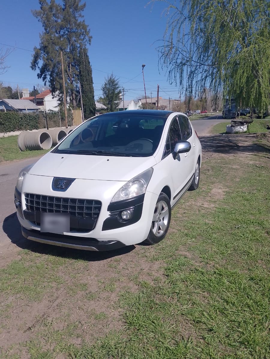 Un Peugeot 3008 blanco recién lavado, estacionado en el pasto frente al taller