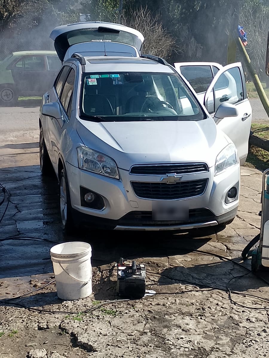 Una Chevrolet Tracker gris con las puertas y el baúl abiertos, en pleno lavado